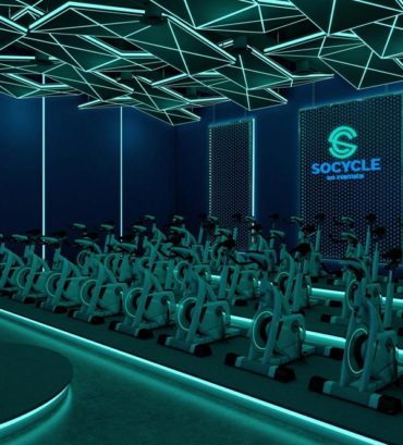 3D Rendering of an indoor cycling class with green led lights and dark blue walls